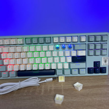Mechanical keyboard with RGB backlighting on a wooden surface, blue screen in the background