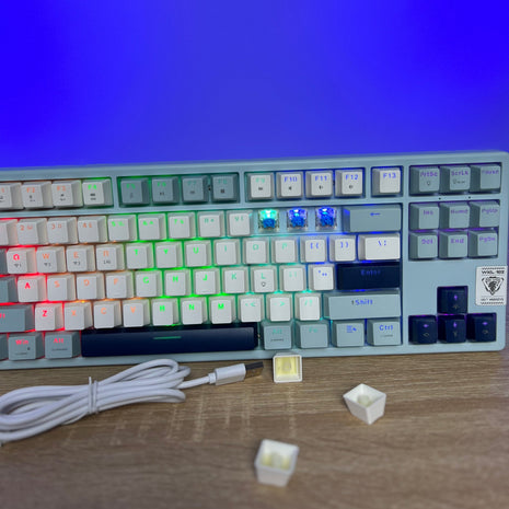 Mechanical keyboard with RGB backlighting on a wooden surface, blue screen in the background