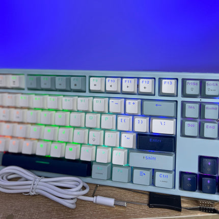 Mechanical keyboard with RGB lighting on a wooden surface against a blue screen background