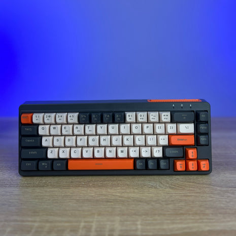 Mechanical keyboard with orange accents on a wooden surface and gradient blue background